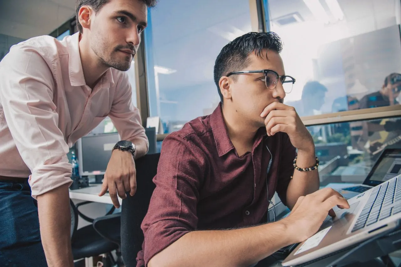 Dos compañeros revisando juntos un trabajo en la laptop